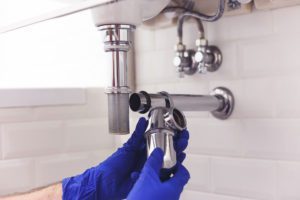 Plumber repairs and maintains chrome siphon under the washbasin