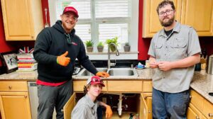 Three workers finishing a job on a kitchen sink