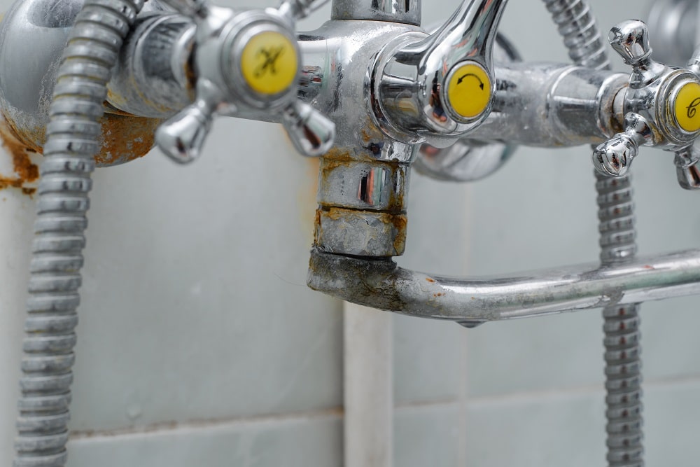 Close-up rusty faucet, plumbing connection with damage and plaque in the bathroom.
