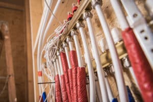 A close view of neatly arranged pipes and electrical wires on a wall at a construction site, showcasing the ongoing preparations for building development.