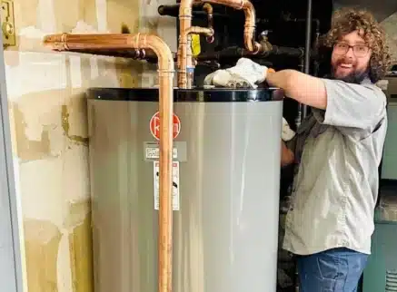 Spartan Plumbing technician connecting copper piping on a newly installed tank water heater