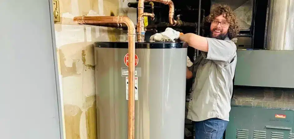 Spartan Plumbing technician connecting copper piping on a newly installed tank water heater